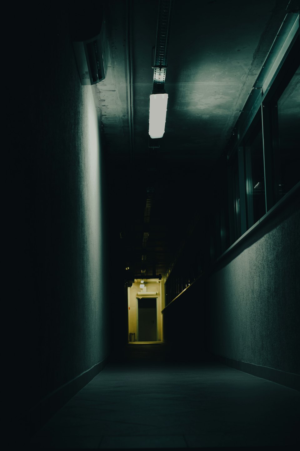 Empty concrete hallway leading to a dimly lit door.